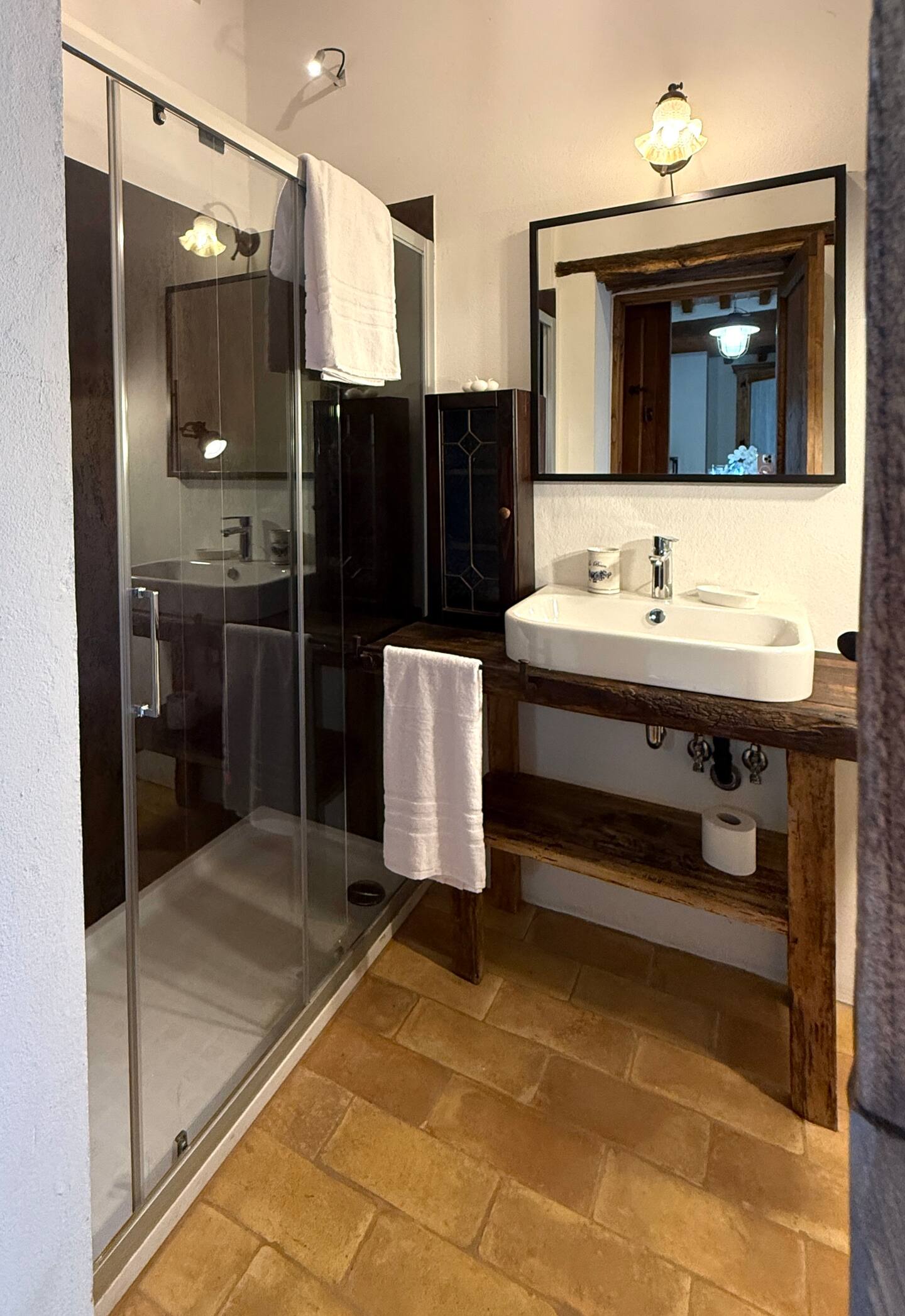 Bagno della Torre della Soara: specchio moderno con cornice nera che riflette l'architettura interna, lavabo di design su ripiano in legno antico e box doccia spazioso con dettagli contemporanei. Bagno della Torre della Soara: specchio moderno con cornice nera che riflette l'architettura interna, lavabo di design su ripiano in legno antico e box doccia spazioso con dettagli contemporanei.