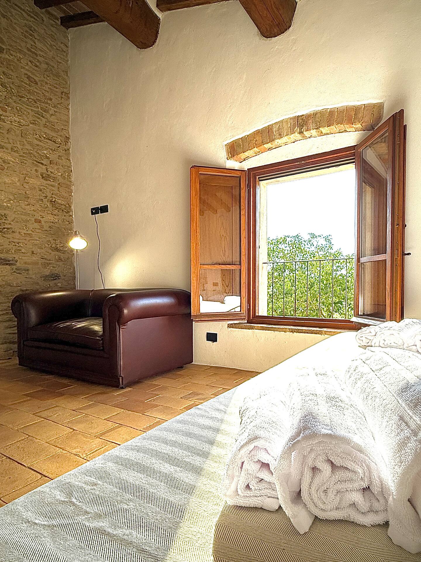 Angolo relax nella camera da letto: divano in pelle, pavimento in cotto e finestra aperta con vista sul verde e arco in mattoni a vista. Angolo relax nella camera da letto: divano in pelle, pavimento in cotto e finestra aperta con vista sul verde e arco in mattoni a vista.