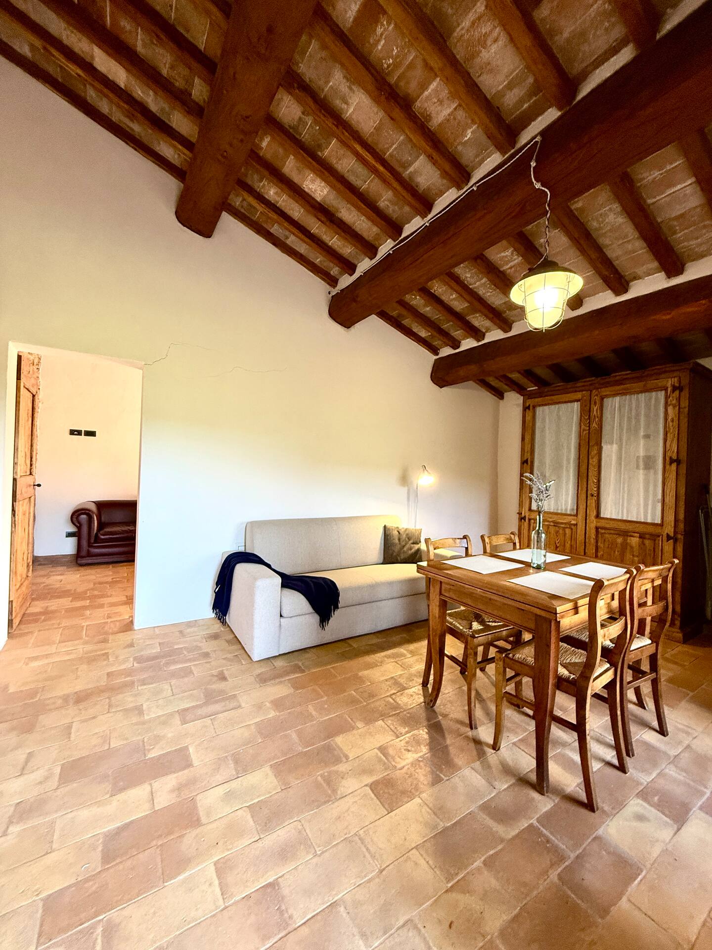 Ampio soggiorno della Torre della Soara con soffitto a travi, pavimento in cotto e cucina attrezzata a scomparsa all'interno di un elegante armadio in legno antico. Ampio soggiorno della Torre della Soara con soffitto a travi, pavimento in cotto e cucina attrezzata a scomparsa all'interno di un elegante armadio in legno antico.